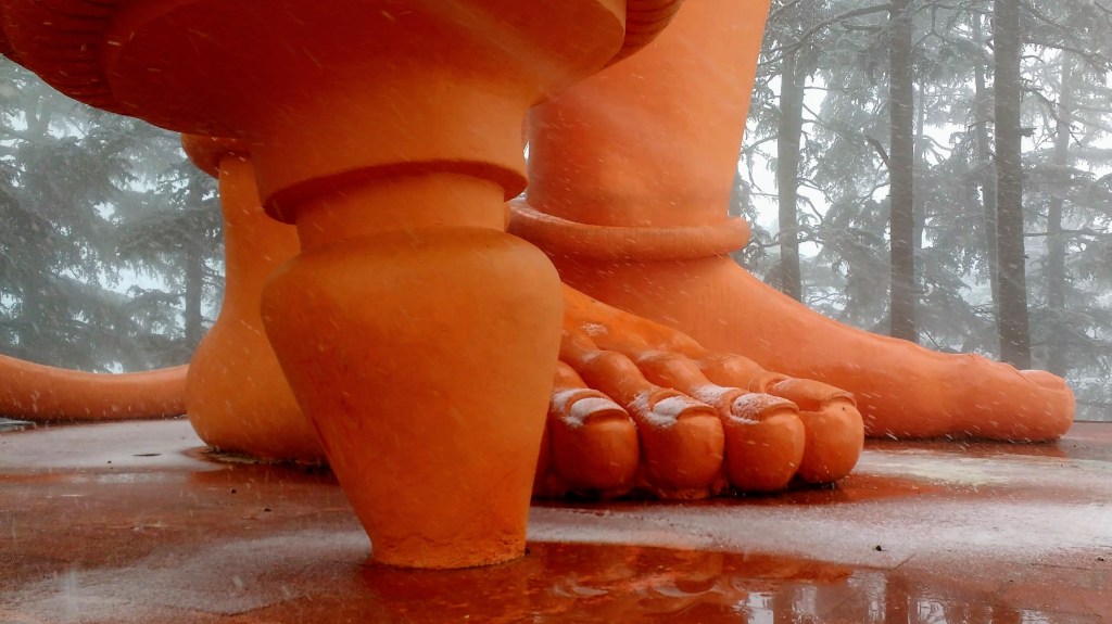 foot of the giant hanuman statue covered in snow from temple in Shimla, Himachal Pradesh.