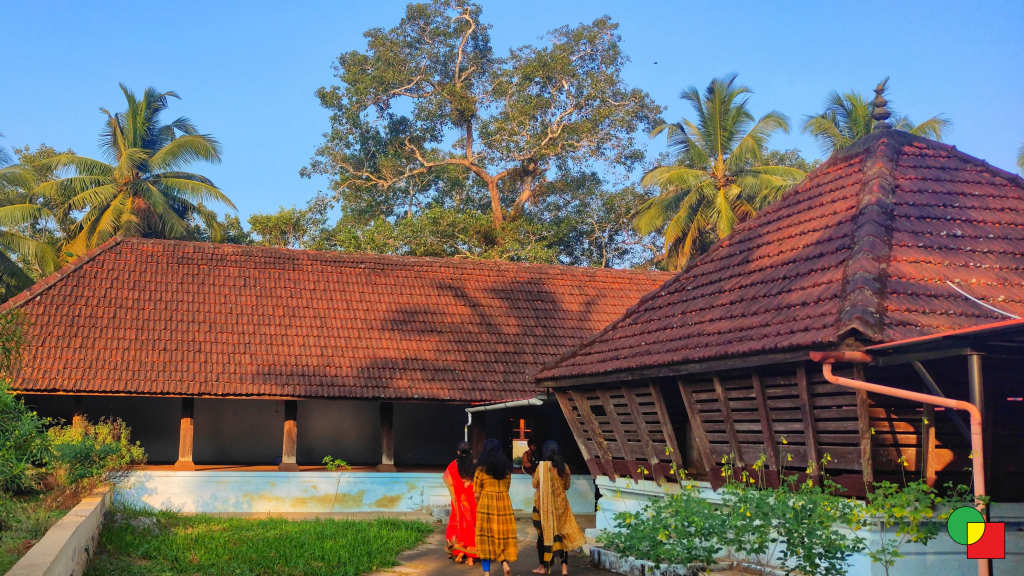 A Kerala temple illuminated by soft morning light, surrounded by lush greenery.