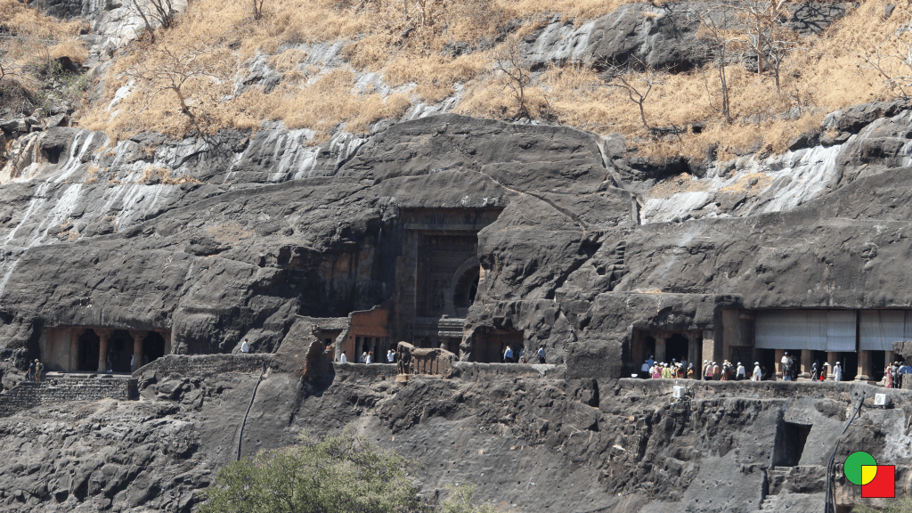 Rows of rock-cut Buddhist caves carved into a curving basalt cliff above the Waghur river gorge at Ajanta, Maharashtra.